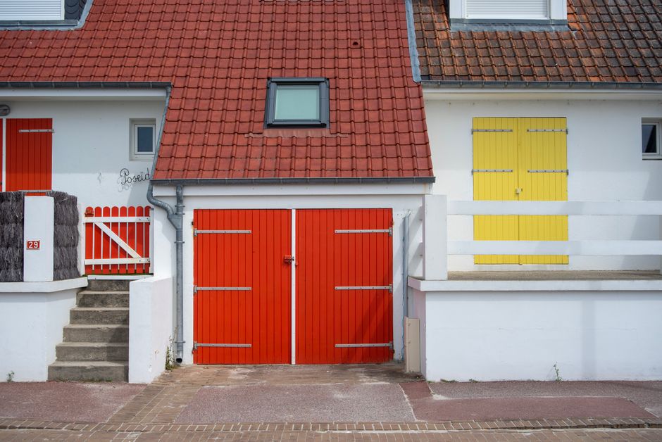 House front painted in bright yellow with red doors.
