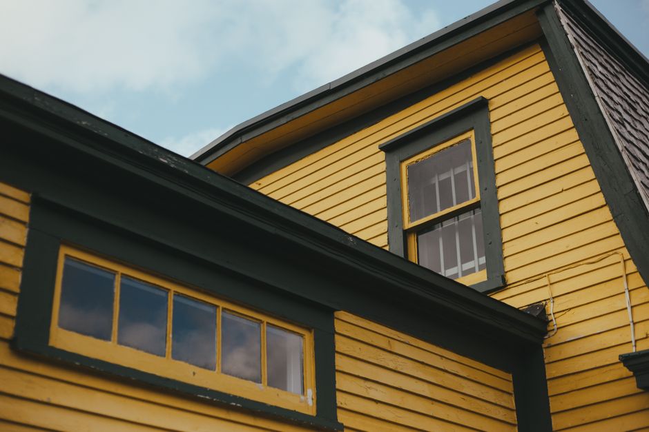 Yellow house with green painted trim seen from below.