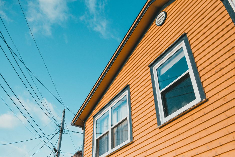 Yellow painted wooden house under a blue sky.