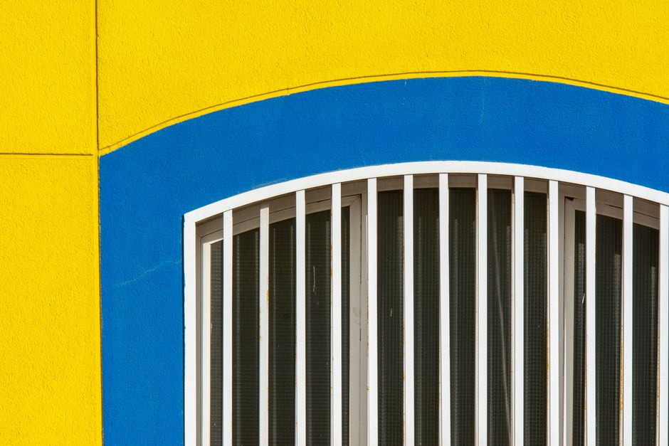 Yellow and blue painted wall around an arched window.