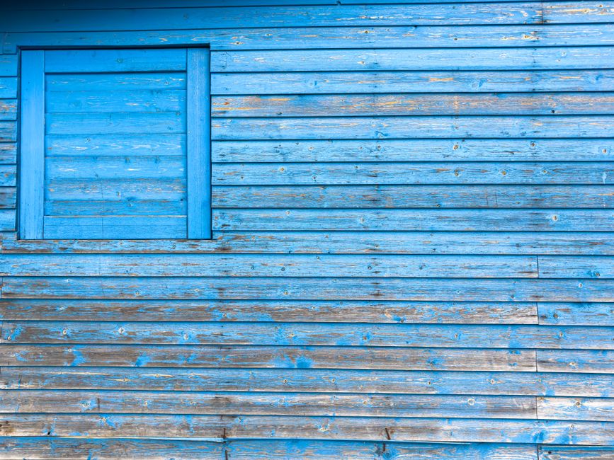 Blue wall with peeling paint ready for scraping and prep.