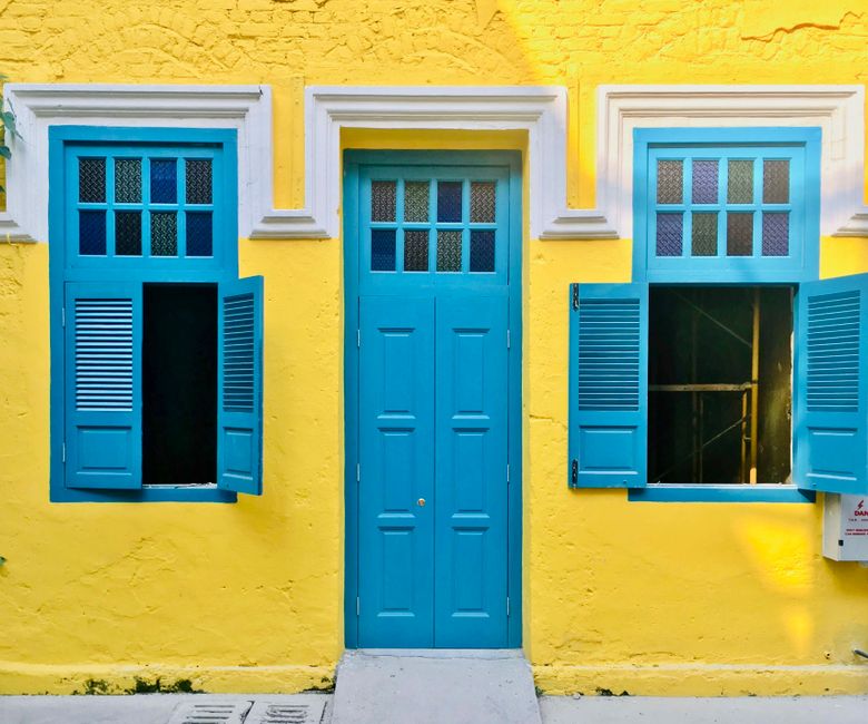 Yellow painted house front with a blue door.